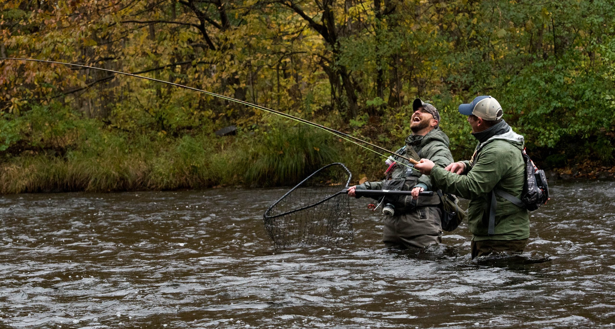 Fishermen laughing in a river while fishing
